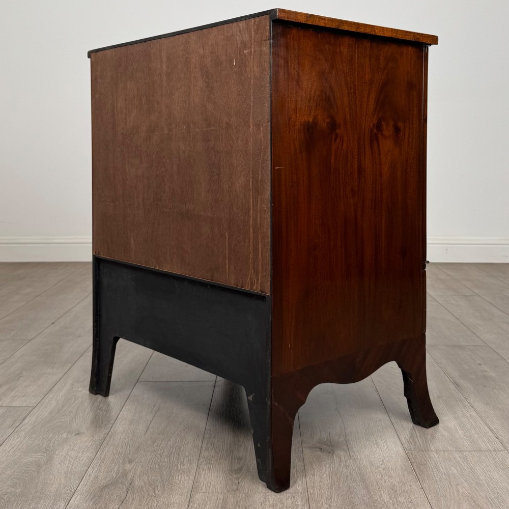 A 20th-century mahogany serpentine cupboard featuring flame mahogany oval door panels, chevron veneering, a lower drawer with brass ring handles, and splayed bracket feet. View VII