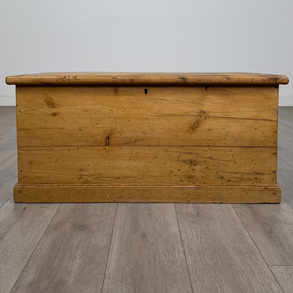 A 19th-century Victorian pine blanket box featuring a flat hinged lid, visible wood grain, central keyhole, and solid plinth base.