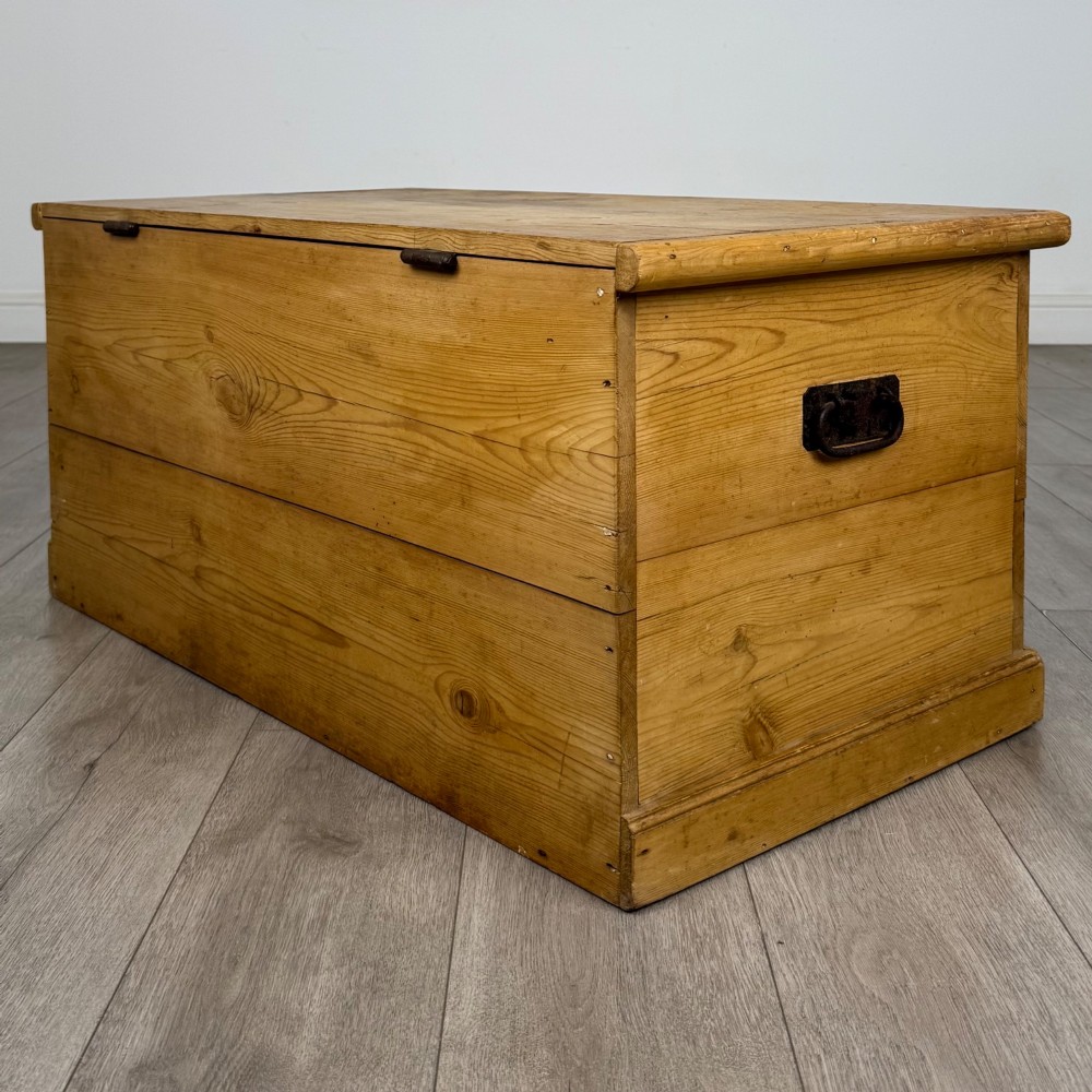 A 19th-century Victorian pine blanket box featuring a flat hinged lid, visible wood grain, central keyhole, and solid plinth base. View VI