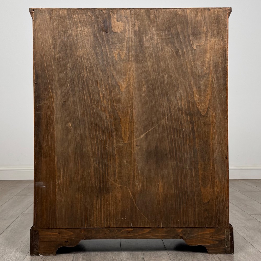 A small medium-brown oak open bookcase featuring two upper shelves and a lower two-door cupboard with carved arched motifs and metal ring handles. View VII