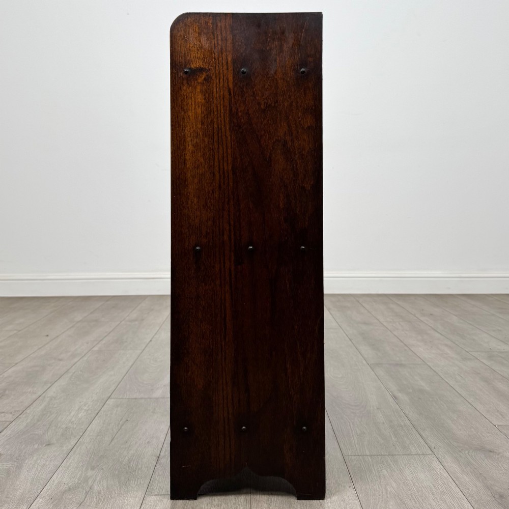 An early 20th-century dark oak display cabinet featuring twin glazed doors, an interior shelf, and a gallery top. View IV