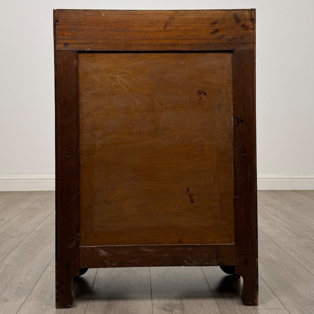 An early 20th-century dark oak display cabinet featuring twin glazed doors, an interior shelf, and a gallery top. View VI