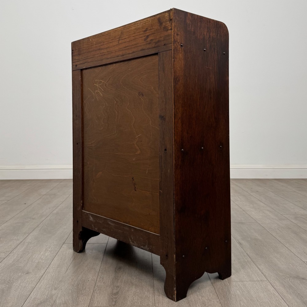 An early 20th-century dark oak display cabinet featuring twin glazed doors, an interior shelf, and a gallery top. View VII