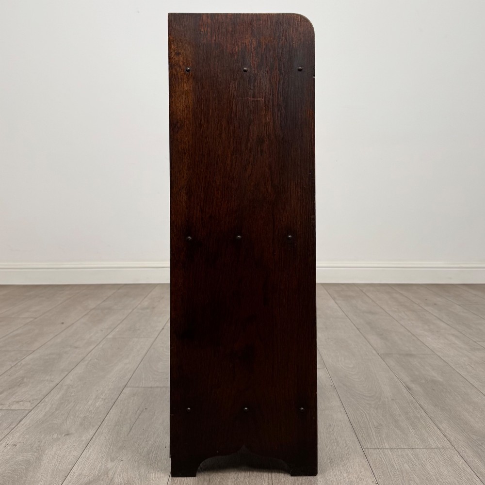 An early 20th-century dark oak display cabinet featuring twin glazed doors, an interior shelf, and a gallery top. View VIII