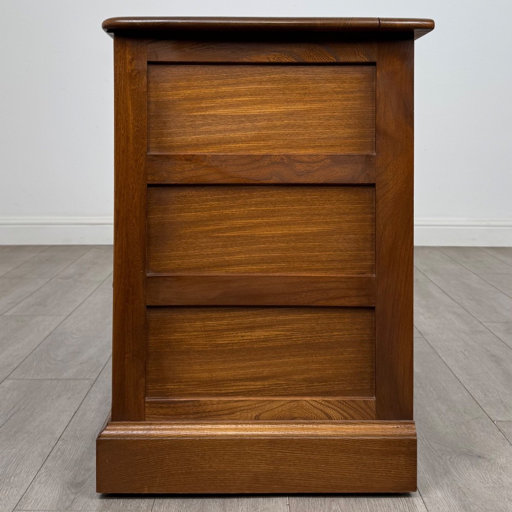 A two-door golden oak storage cupboard featuring geometric panelled doors, turned timber knobs, and a low plinth base. View IV