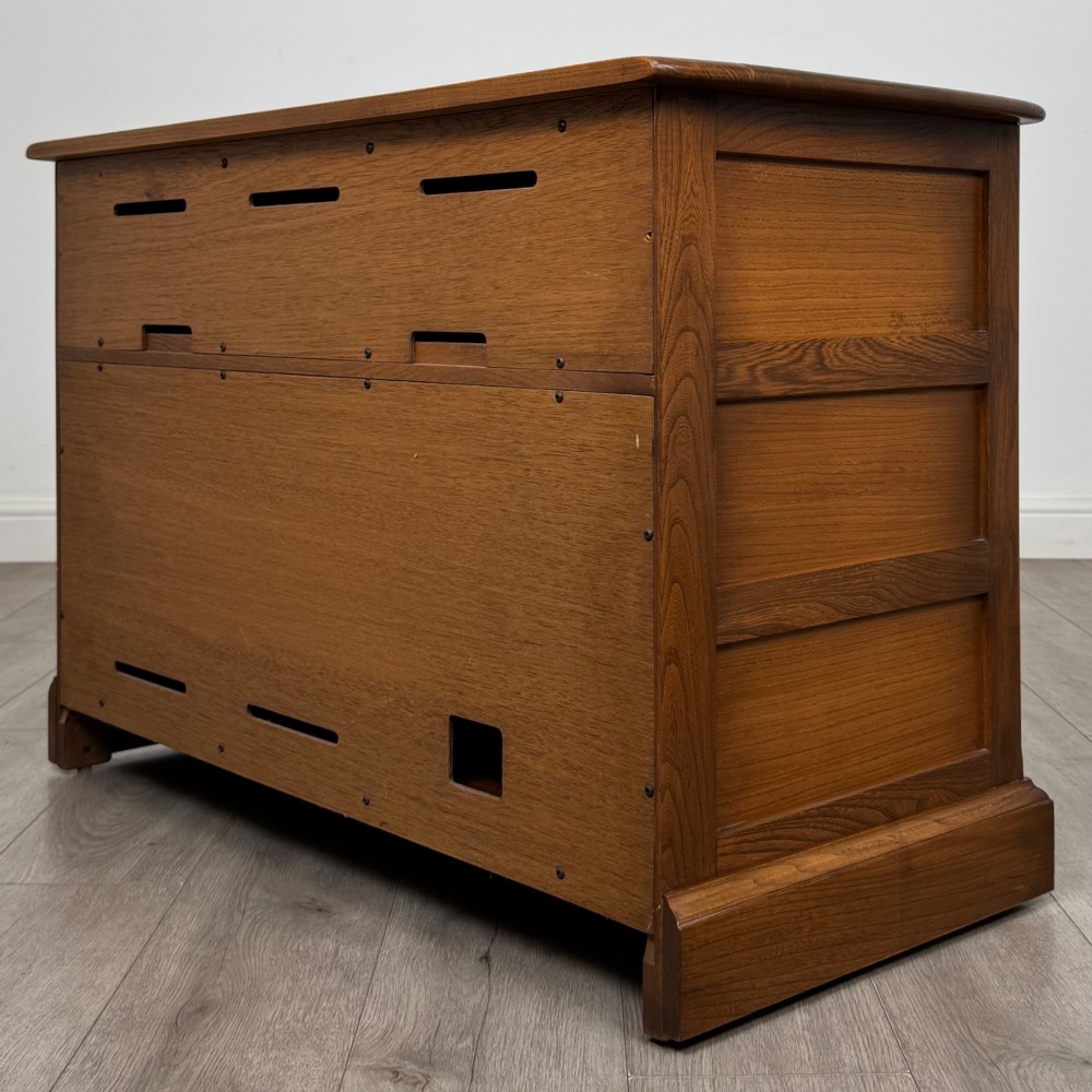 A two-door golden oak storage cupboard featuring geometric panelled doors, turned timber knobs, and a low plinth base. View VII