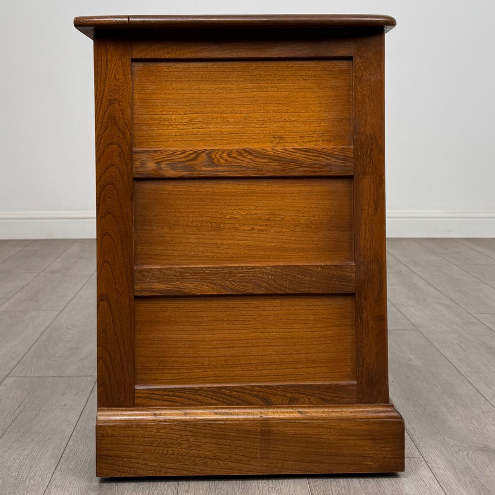 A two-door golden oak storage cupboard featuring geometric panelled doors, turned timber knobs, and a low plinth base. View VIII