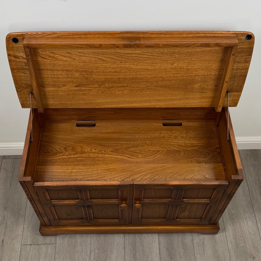 A two-door golden oak storage cupboard featuring geometric panelled doors, turned timber knobs, and a low plinth base. View XI