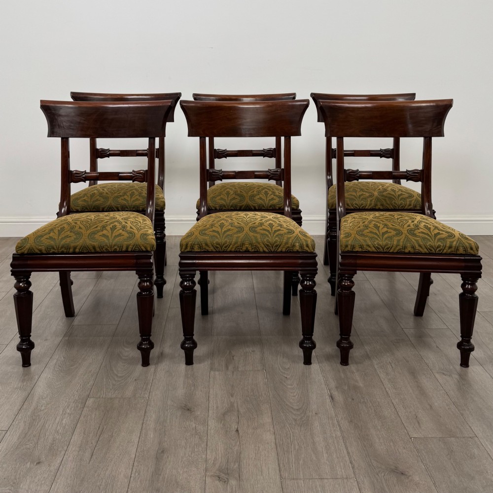 A set of six 19th-century William IV mahogany dining chairs featuring turned front legs, curved back rails, and green patterned fabric seats.