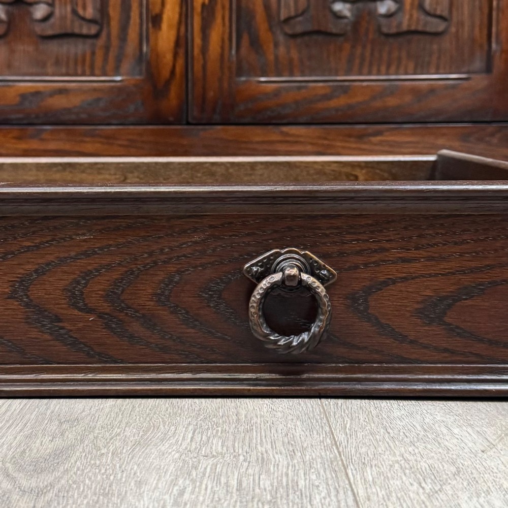 A dark oak display cabinet with a leaded glass central upper cupboard, flanked by open shelves, set atop a lower unit with multiple drawers and carved cupboard doors. View XIII