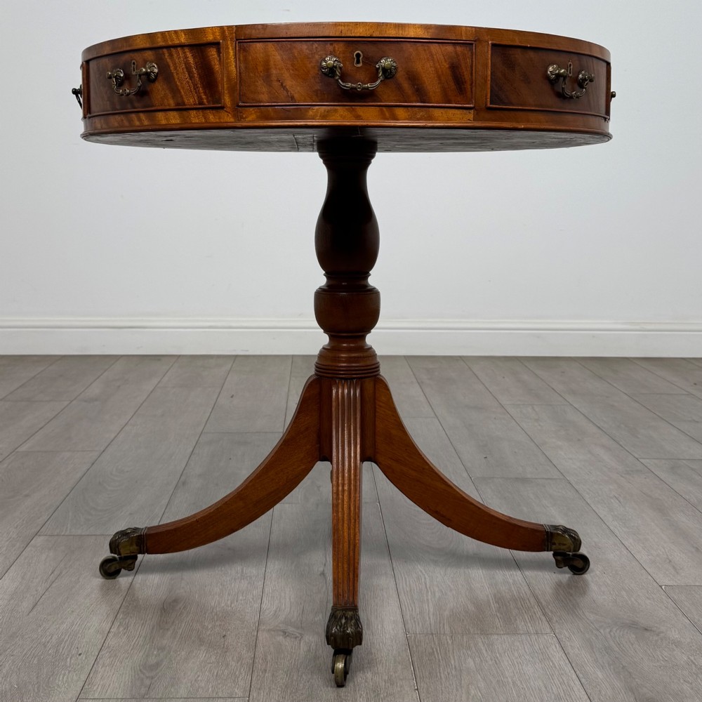 A small Regency style circular mahogany drum table featuring frieze drawers with brass handles, supported by a central turned pedestal and reeded splayed legs on brass castors. View II
