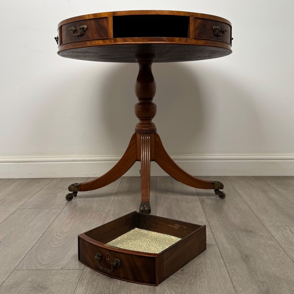 A small Regency style circular mahogany drum table featuring frieze drawers with brass handles, supported by a central turned pedestal and reeded splayed legs on brass castors. View VII