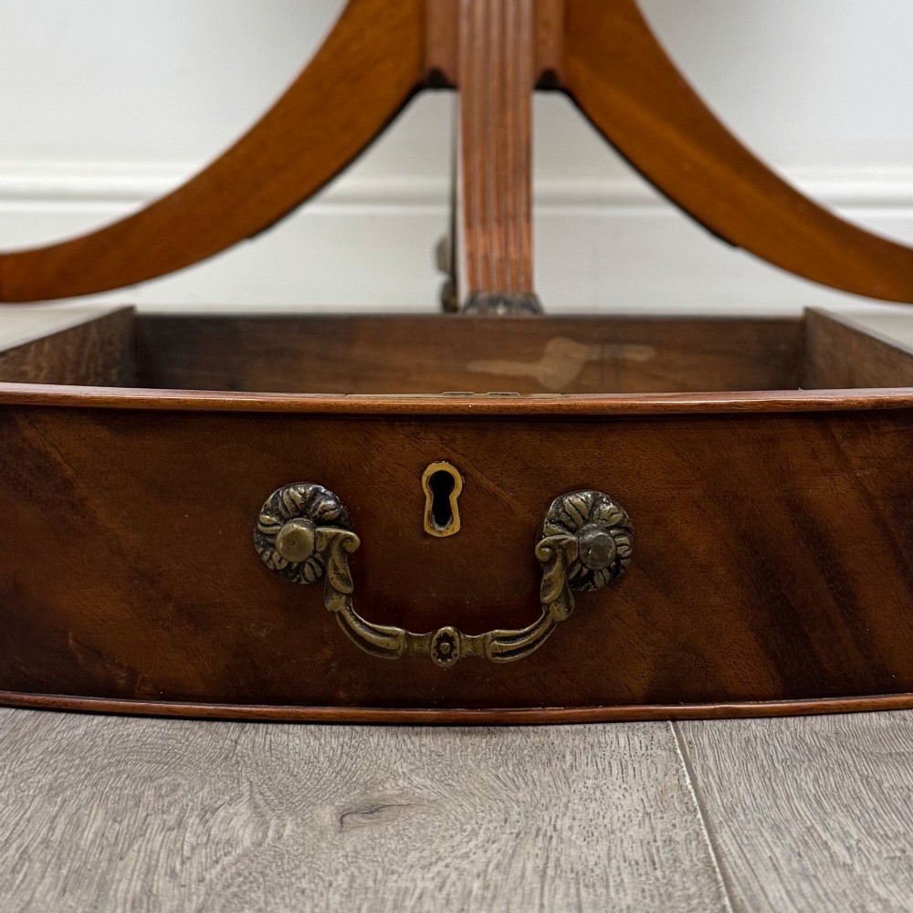 A small Regency style circular mahogany drum table featuring frieze drawers with brass handles, supported by a central turned pedestal and reeded splayed legs on brass castors. View VIII