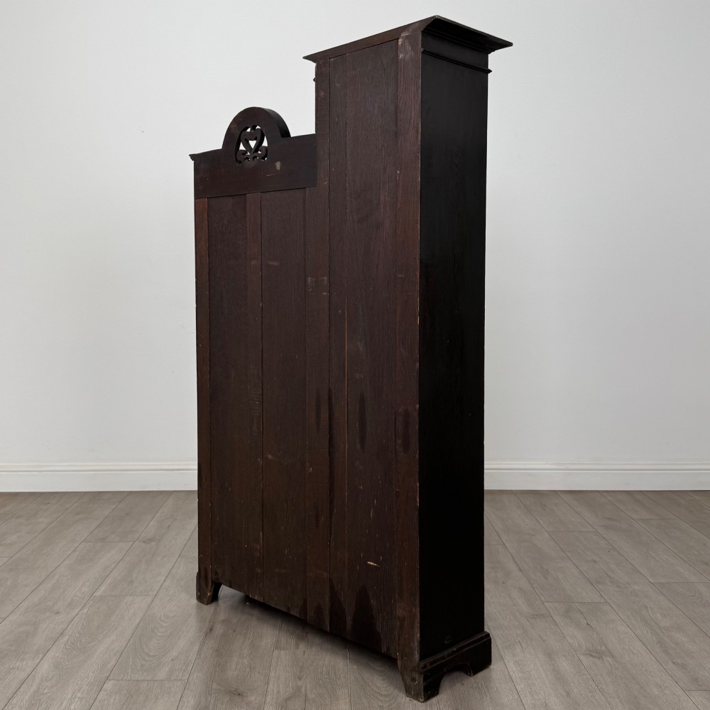 An ebonised oak bureau bookcase featuring an asymmetrical design with a glazed door cabinet, a slanted fall-front writing surface, open shelving, and a heart cutout crest. View VIII
