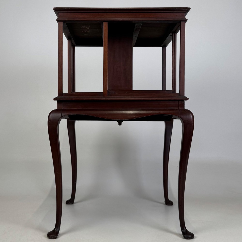 A dark mahogany revolving bookcase featuring a two-tier rotating upper section supported by slender cabriole legs ending in pad feet.