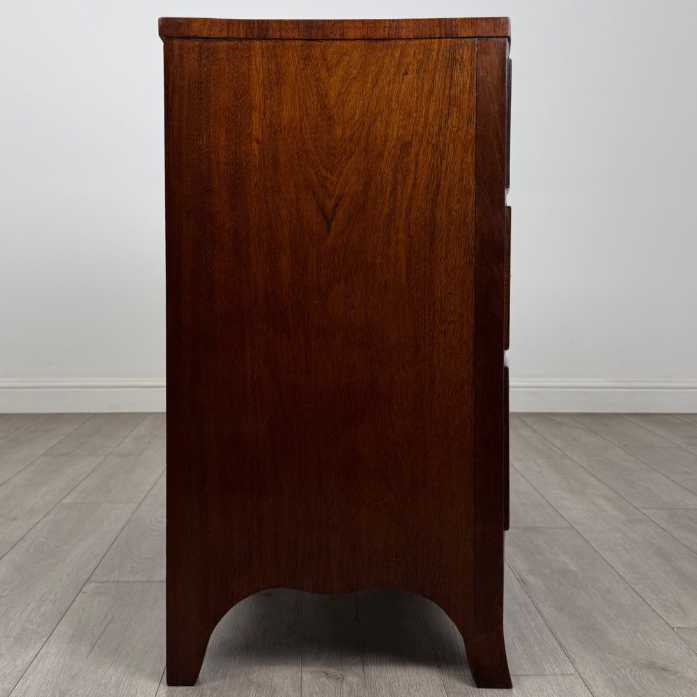 An 18th-century Georgian mahogany bow-front chest of drawers featuring two short over two long drawers with brass oval handles and splayed bracket feet. View VII