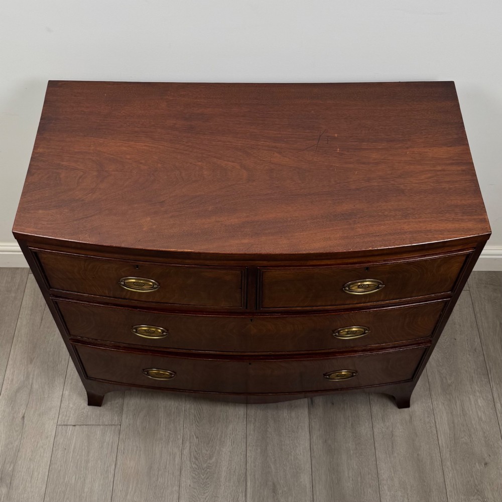 An 18th-century Georgian mahogany bow-front chest of drawers featuring two short over two long drawers with brass oval handles and splayed bracket feet. View IX