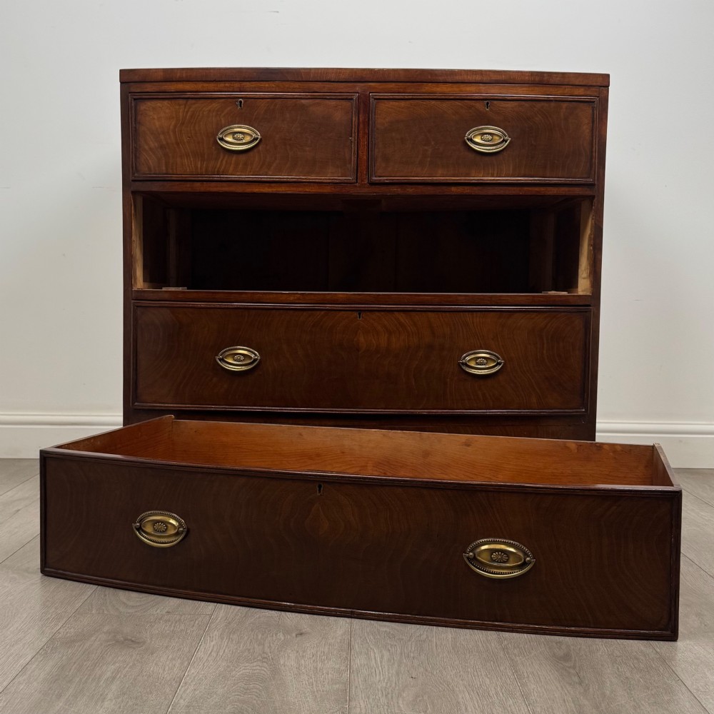 An 18th-century Georgian mahogany bow-front chest of drawers featuring two short over two long drawers with brass oval handles and splayed bracket feet. View X