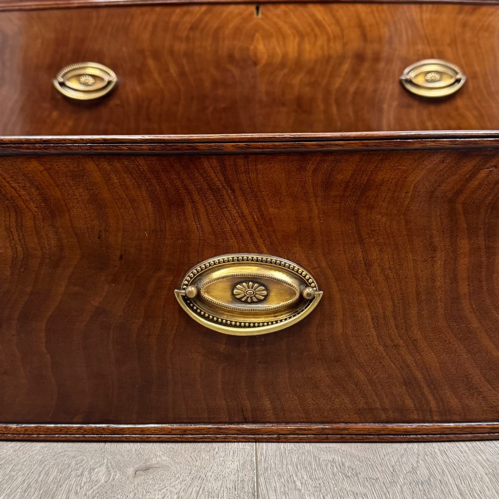 An 18th-century Georgian mahogany bow-front chest of drawers featuring two short over two long drawers with brass oval handles and splayed bracket feet. View XI