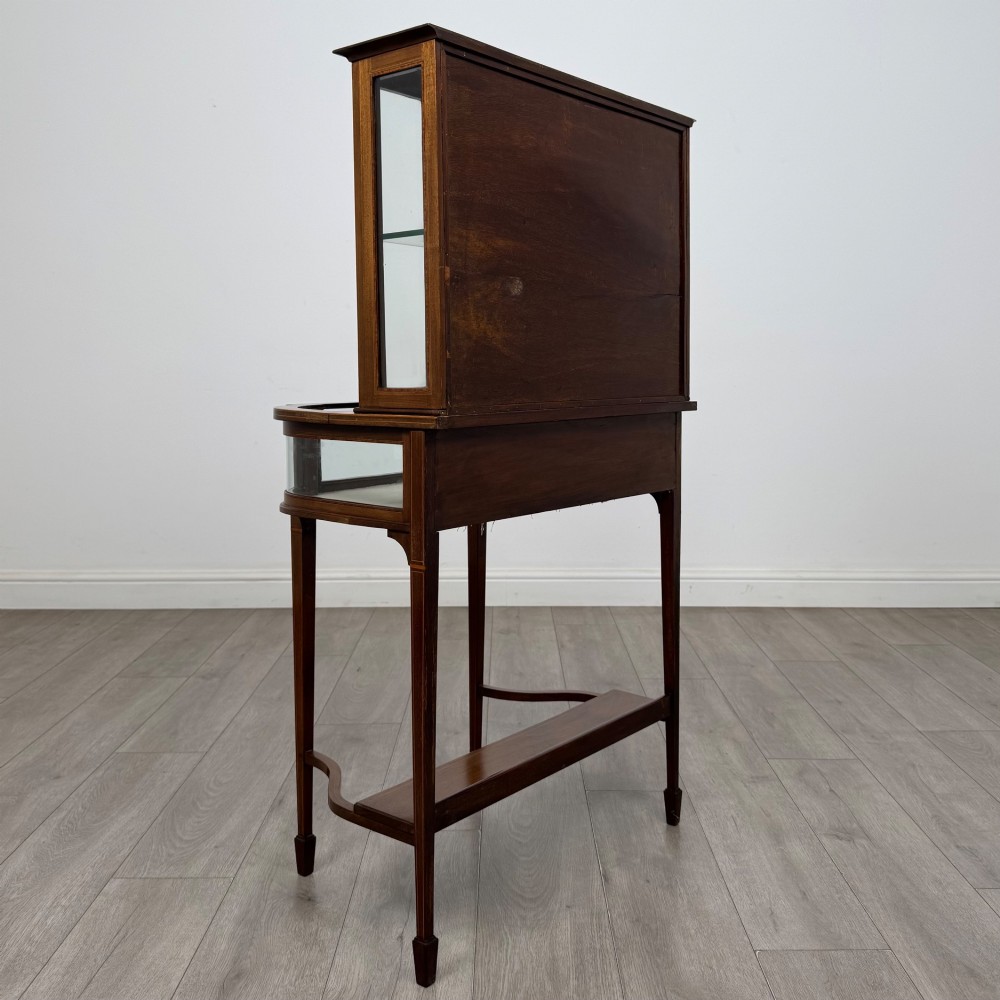 An Edwardian mahogany glazed display cabinet featuring tapered legs, line inlay detailing, glass shelves, and a lower undertier shelf. View V