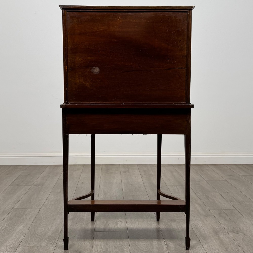 An Edwardian mahogany glazed display cabinet featuring tapered legs, line inlay detailing, glass shelves, and a lower undertier shelf. View VI
