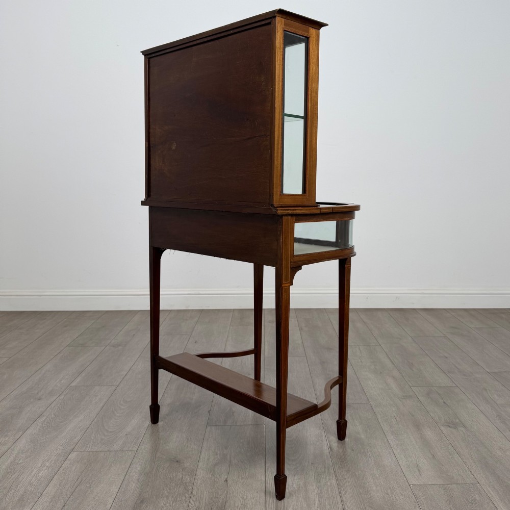 An Edwardian mahogany glazed display cabinet featuring tapered legs, line inlay detailing, glass shelves, and a lower undertier shelf. View VII