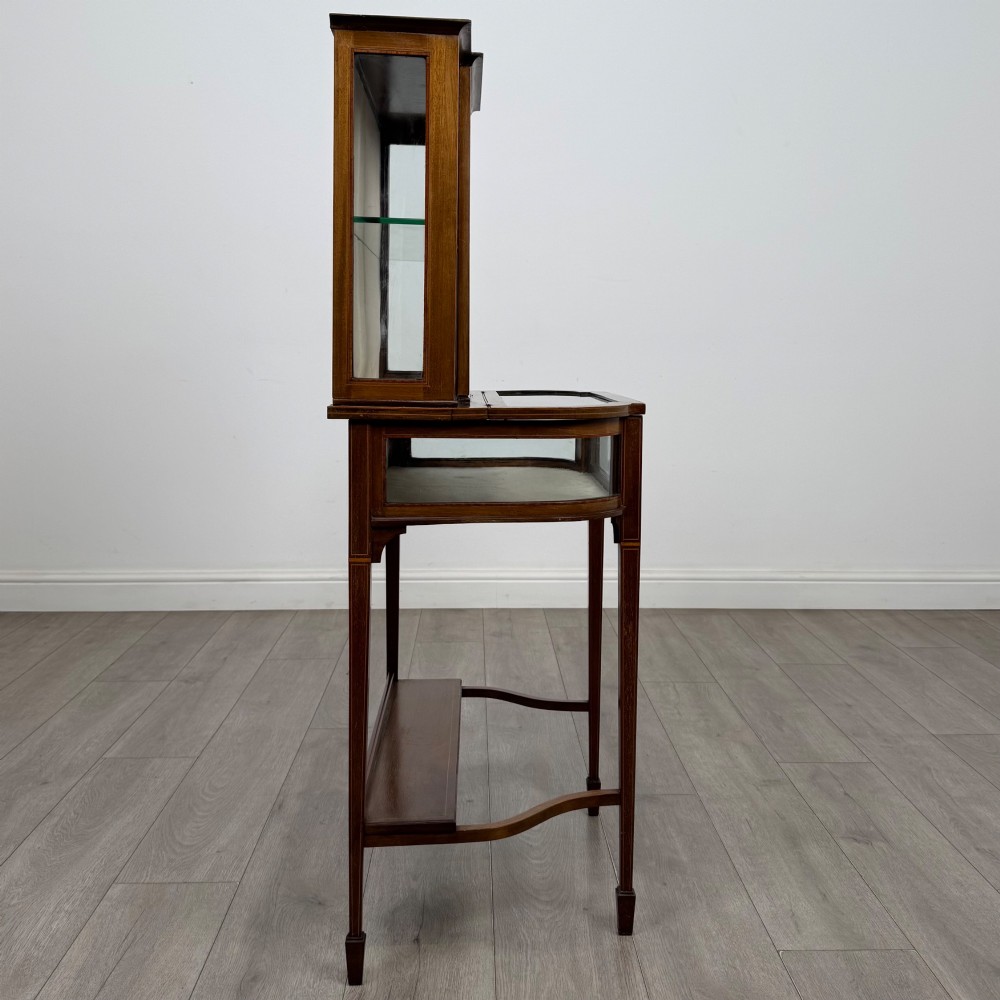 An Edwardian mahogany glazed display cabinet featuring tapered legs, line inlay detailing, glass shelves, and a lower undertier shelf. View VIII