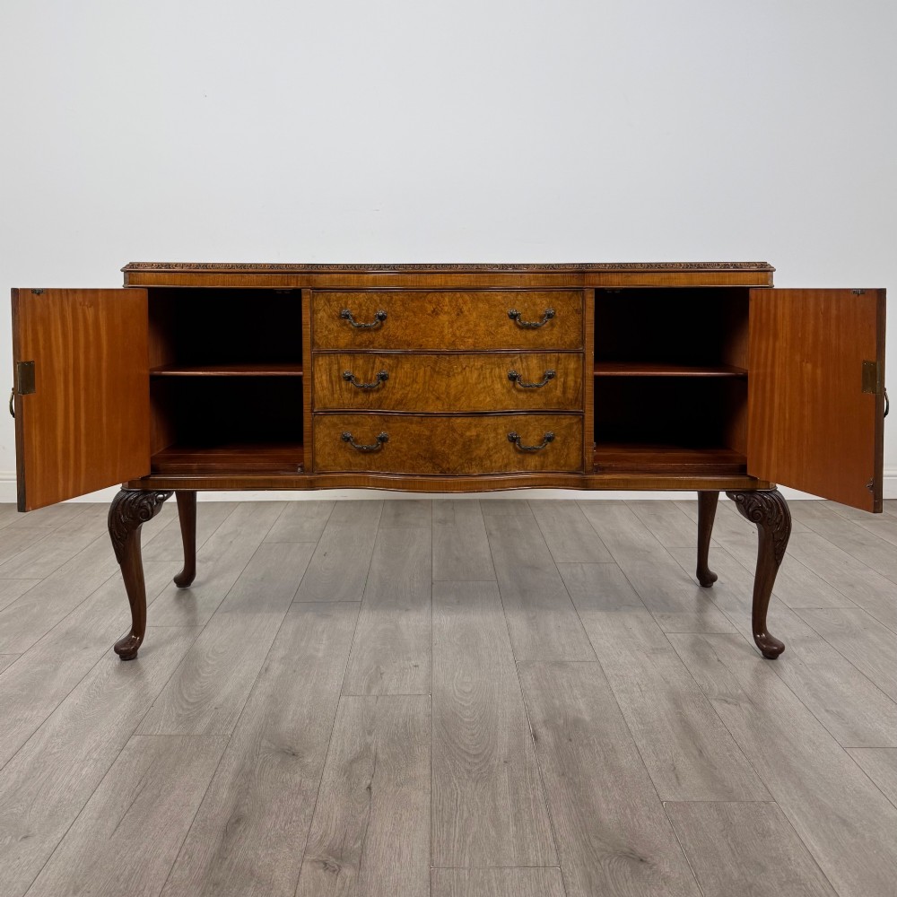 An Edwardian burr walnut sideboard featuring three central drawers flanked by two cupboard doors, set on carved cabriole legs. View II
