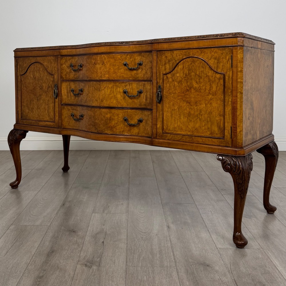 An Edwardian burr walnut sideboard featuring three central drawers flanked by two cupboard doors, set on carved cabriole legs. View III