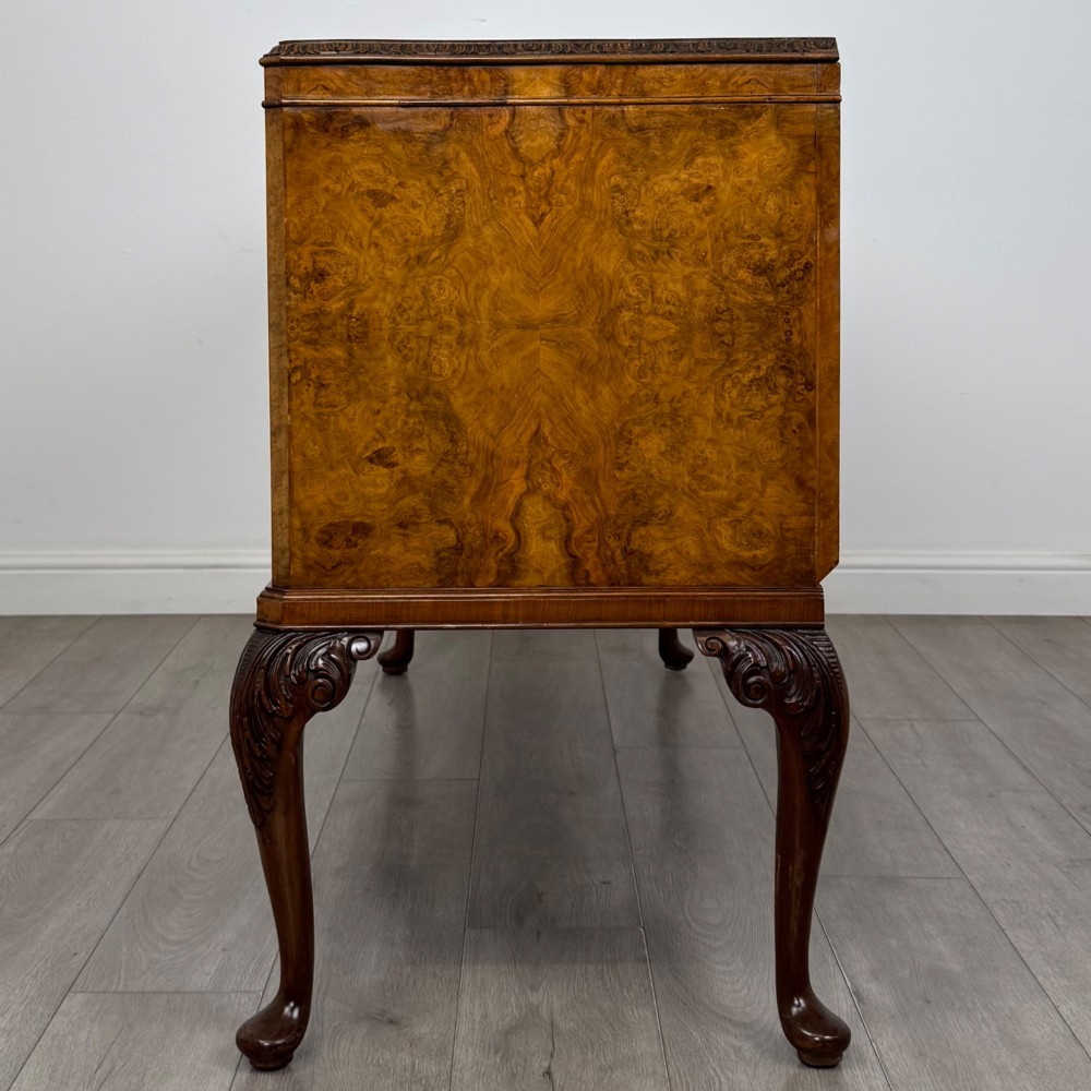 An Edwardian burr walnut sideboard featuring three central drawers flanked by two cupboard doors, set on carved cabriole legs. View IV