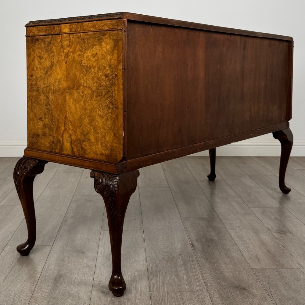 An Edwardian burr walnut sideboard featuring three central drawers flanked by two cupboard doors, set on carved cabriole legs. View V