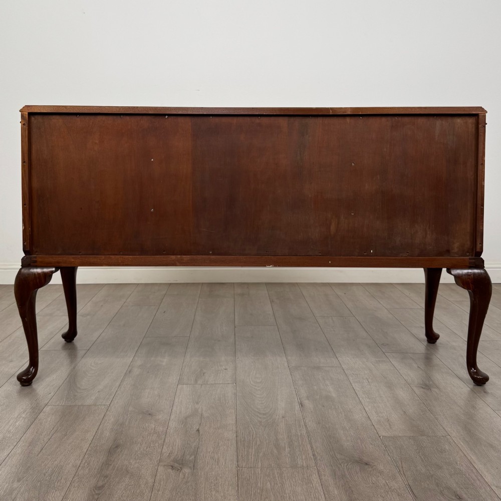 An Edwardian burr walnut sideboard featuring three central drawers flanked by two cupboard doors, set on carved cabriole legs. View VI