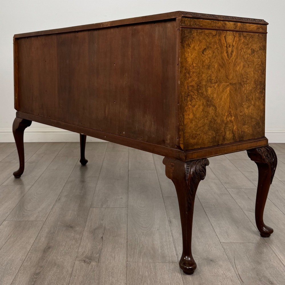 An Edwardian burr walnut sideboard featuring three central drawers flanked by two cupboard doors, set on carved cabriole legs. View VII