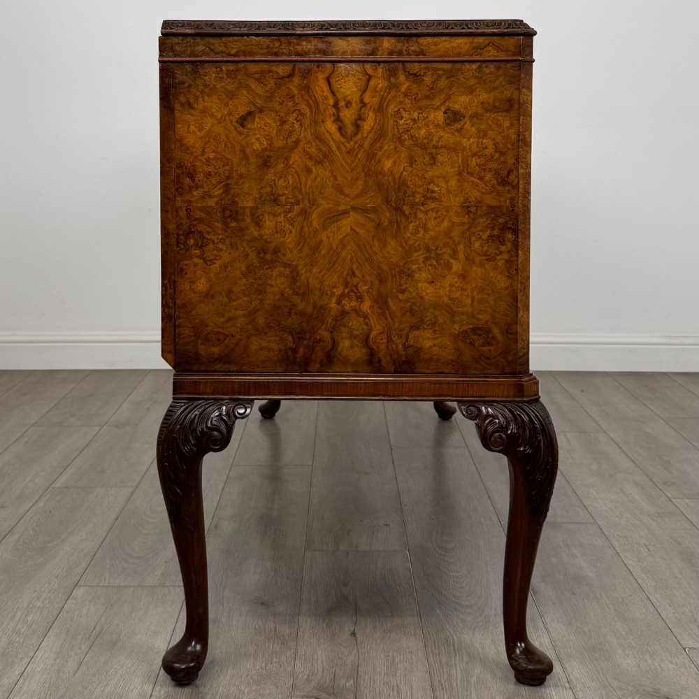 An Edwardian burr walnut sideboard featuring three central drawers flanked by two cupboard doors, set on carved cabriole legs. View VIII