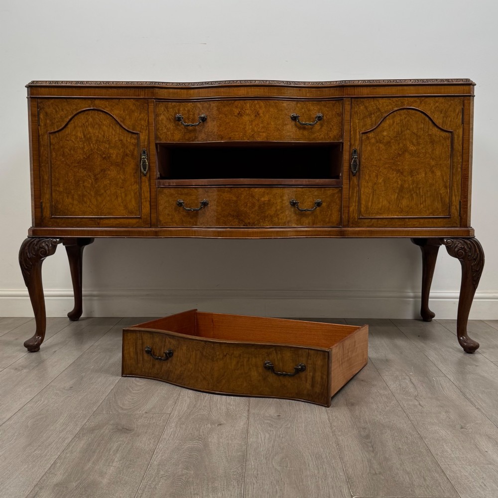 An Edwardian burr walnut sideboard featuring three central drawers flanked by two cupboard doors, set on carved cabriole legs. View XI