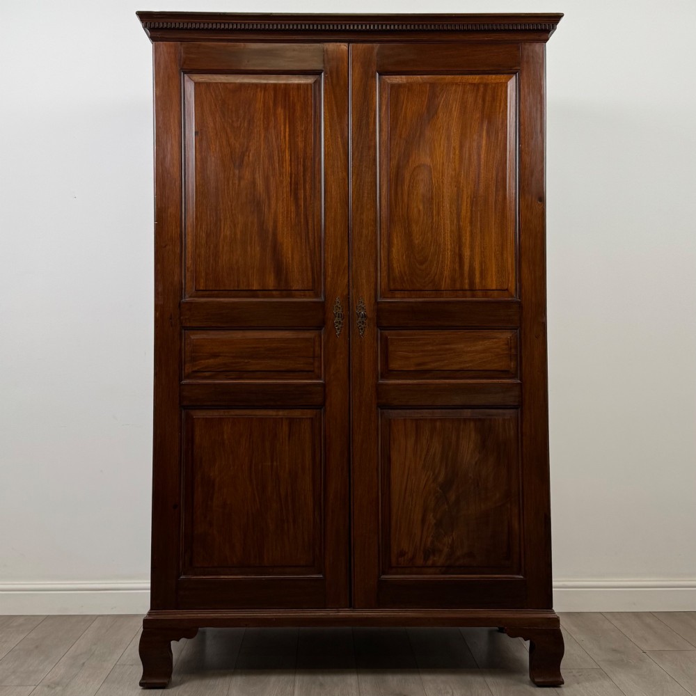 An 18th-century Georgian mahogany two-door wardrobe featuring fielded panel doors, a dentil-moulded cornice, and shaped bracket feet.
