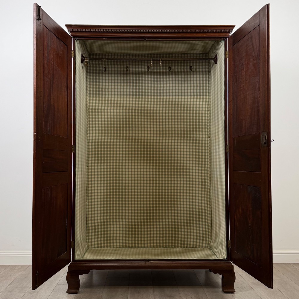 An 18th-century Georgian mahogany two-door wardrobe featuring fielded panel doors, a dentil-moulded cornice, and shaped bracket feet. View II