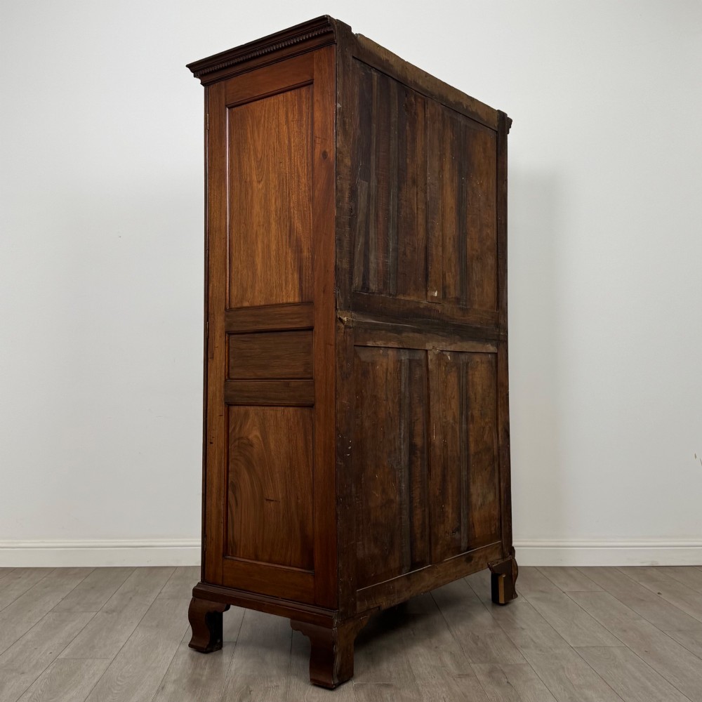 An 18th-century Georgian mahogany two-door wardrobe featuring fielded panel doors, a dentil-moulded cornice, and shaped bracket feet. View V