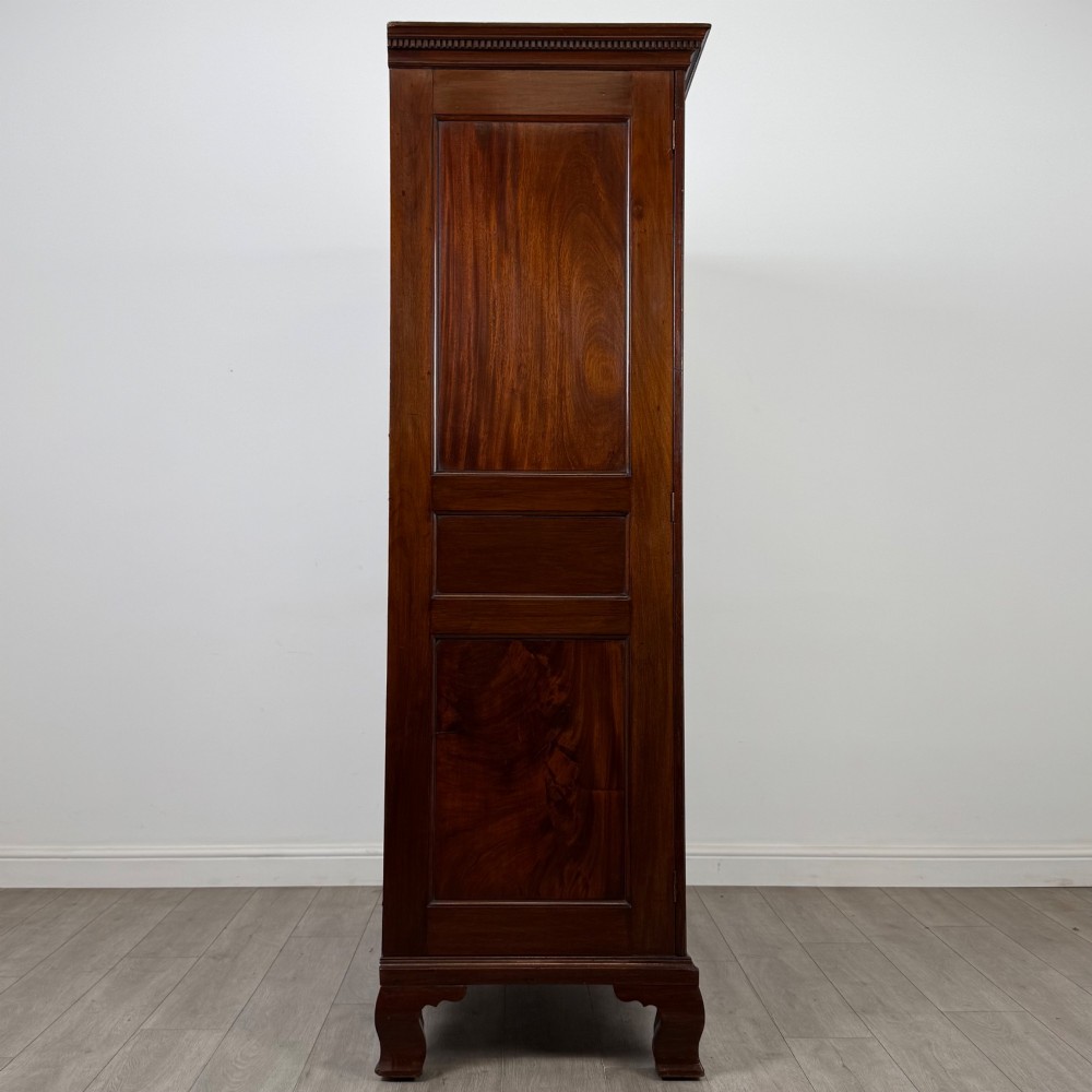 An 18th-century Georgian mahogany two-door wardrobe featuring fielded panel doors, a dentil-moulded cornice, and shaped bracket feet. View VIII