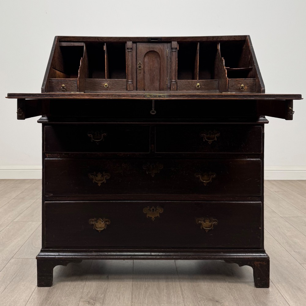 An 18th-century dark oak Georgian bureau with a slant-front writing slope, brass batwing drop handles, and bracket feet. View II
