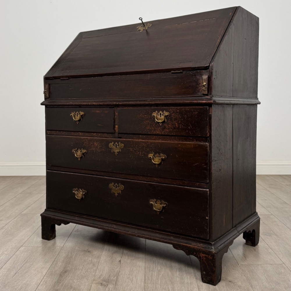 An 18th-century dark oak Georgian bureau with a slant-front writing slope, brass batwing drop handles, and bracket feet. View III