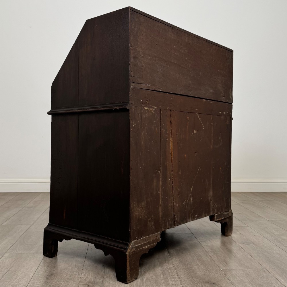 An 18th-century dark oak Georgian bureau with a slant-front writing slope, brass batwing drop handles, and bracket feet. View V