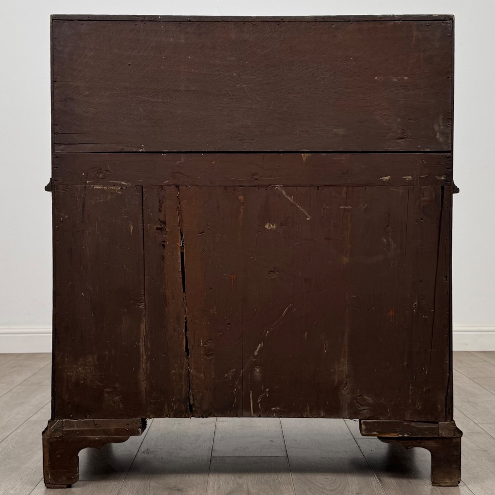 An 18th-century dark oak Georgian bureau with a slant-front writing slope, brass batwing drop handles, and bracket feet. View VI