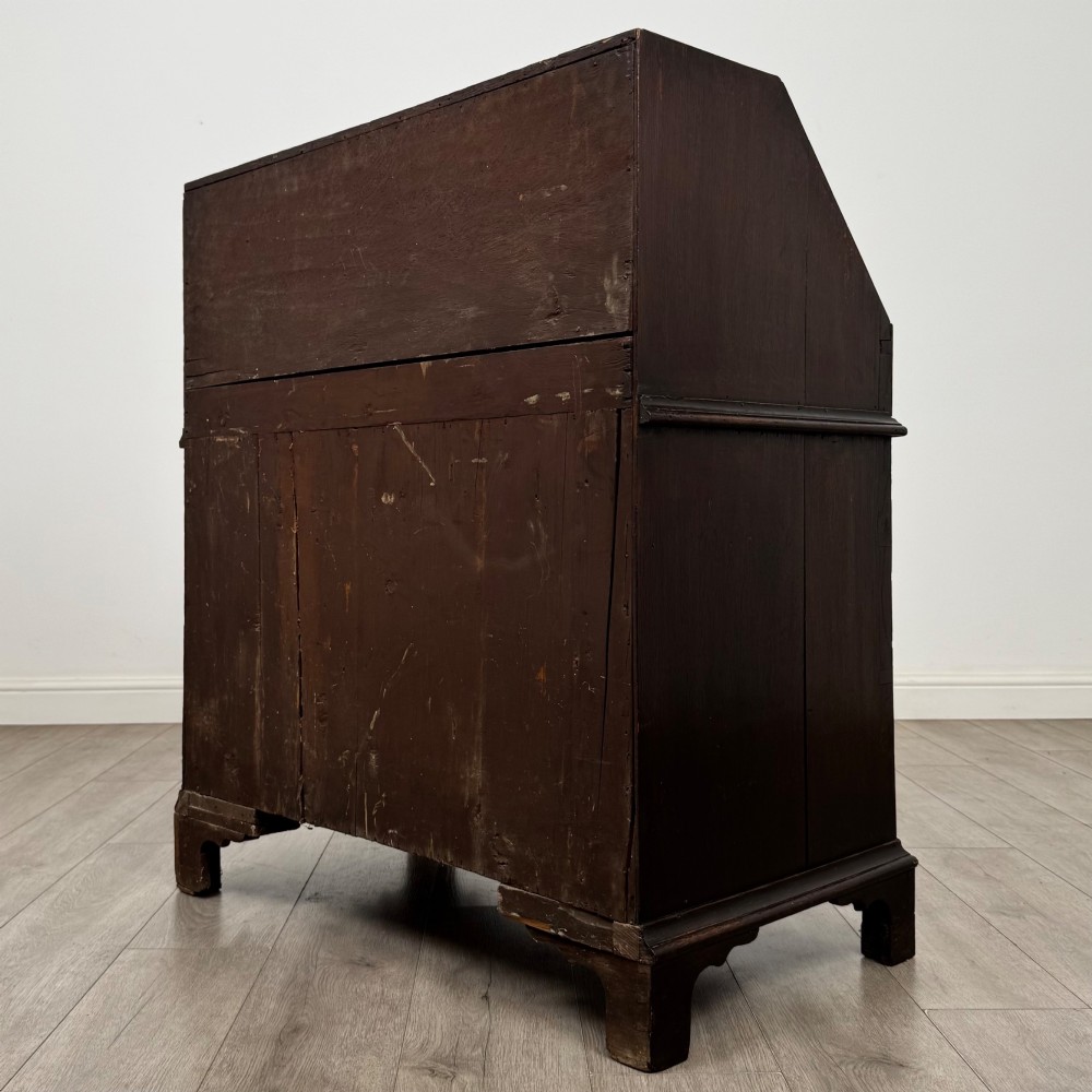 An 18th-century dark oak Georgian bureau with a slant-front writing slope, brass batwing drop handles, and bracket feet. View VII