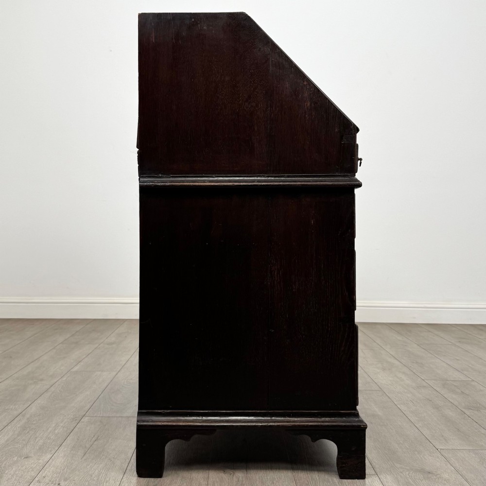 An 18th-century dark oak Georgian bureau with a slant-front writing slope, brass batwing drop handles, and bracket feet. View VIII