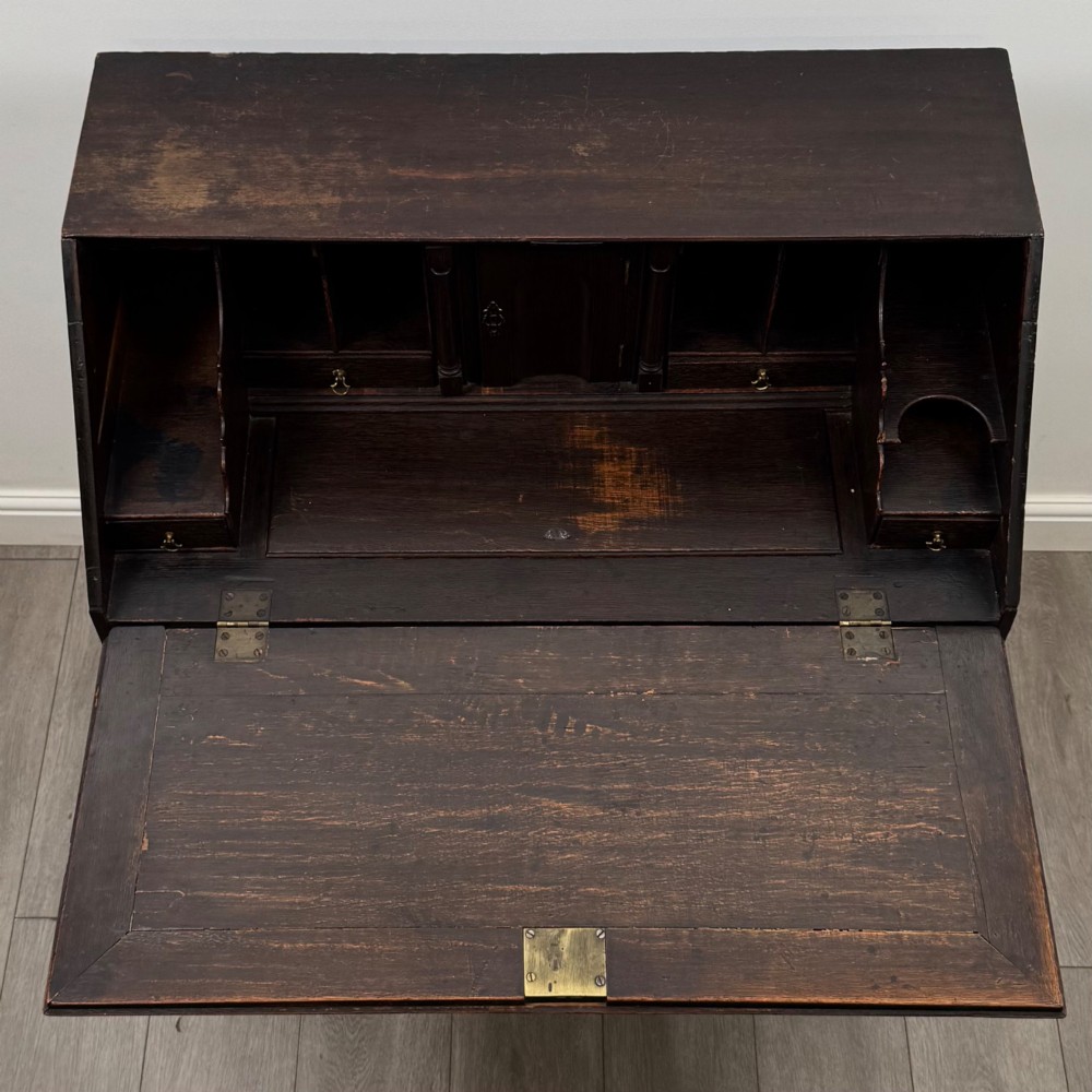 An 18th-century dark oak Georgian bureau with a slant-front writing slope, brass batwing drop handles, and bracket feet. View XI
