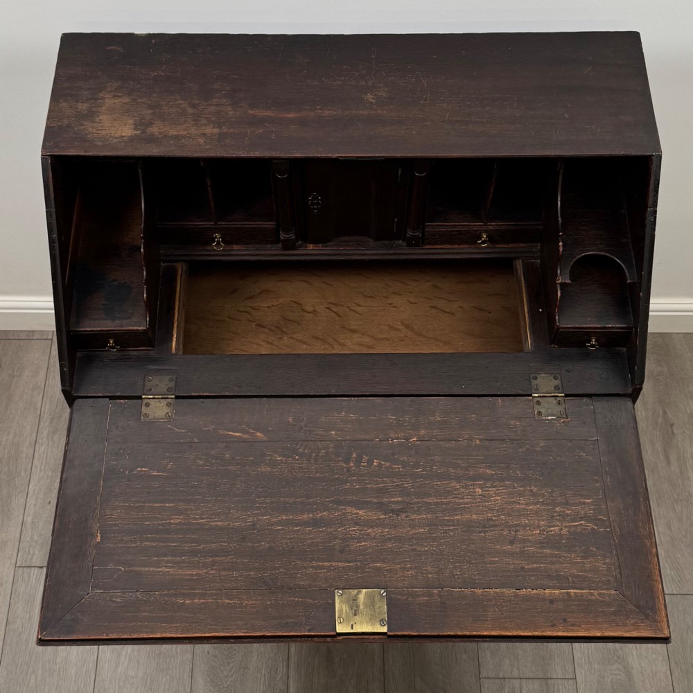 An 18th-century dark oak Georgian bureau with a slant-front writing slope, brass batwing drop handles, and bracket feet. View XII