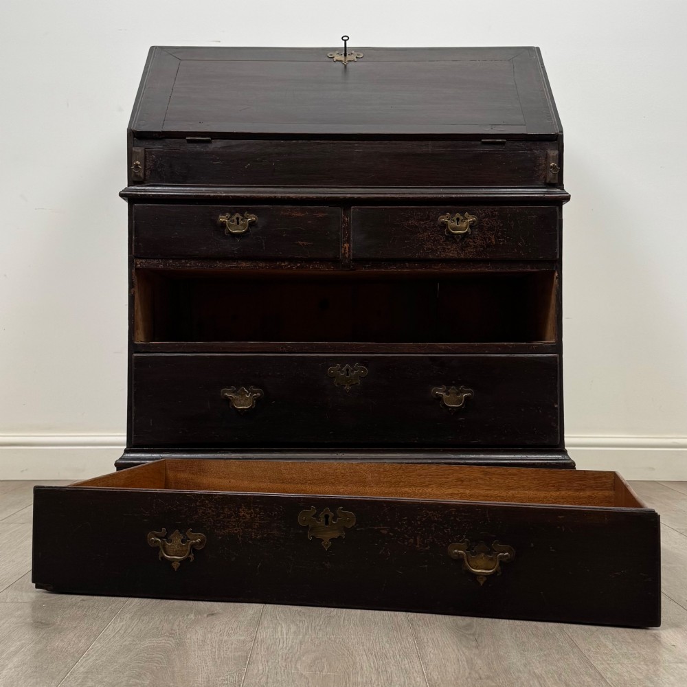 An 18th-century dark oak Georgian bureau with a slant-front writing slope, brass batwing drop handles, and bracket feet. View XIII