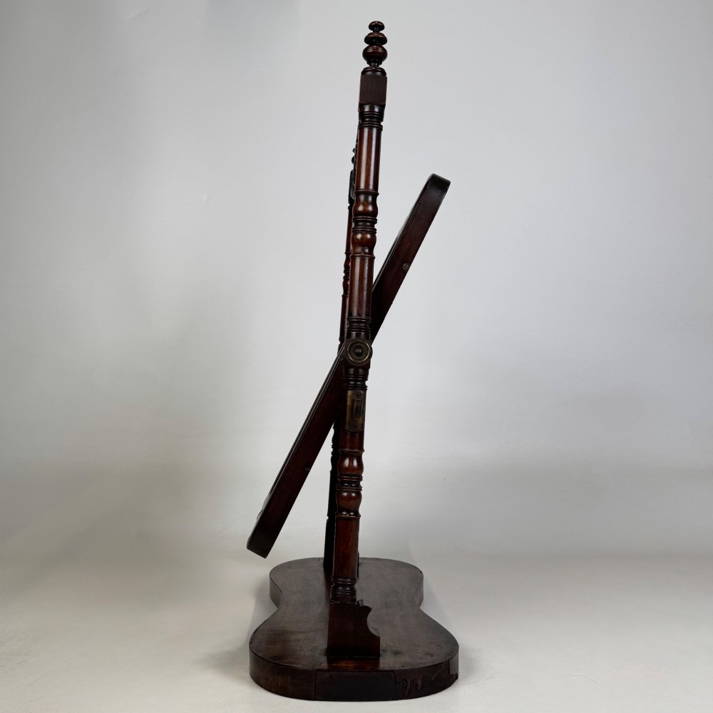 A 19th-century mahogany dressing mirror with turned side columns, carved scrollwork cresting, and an adjustable rectangular glass frame on a shaped base. View V