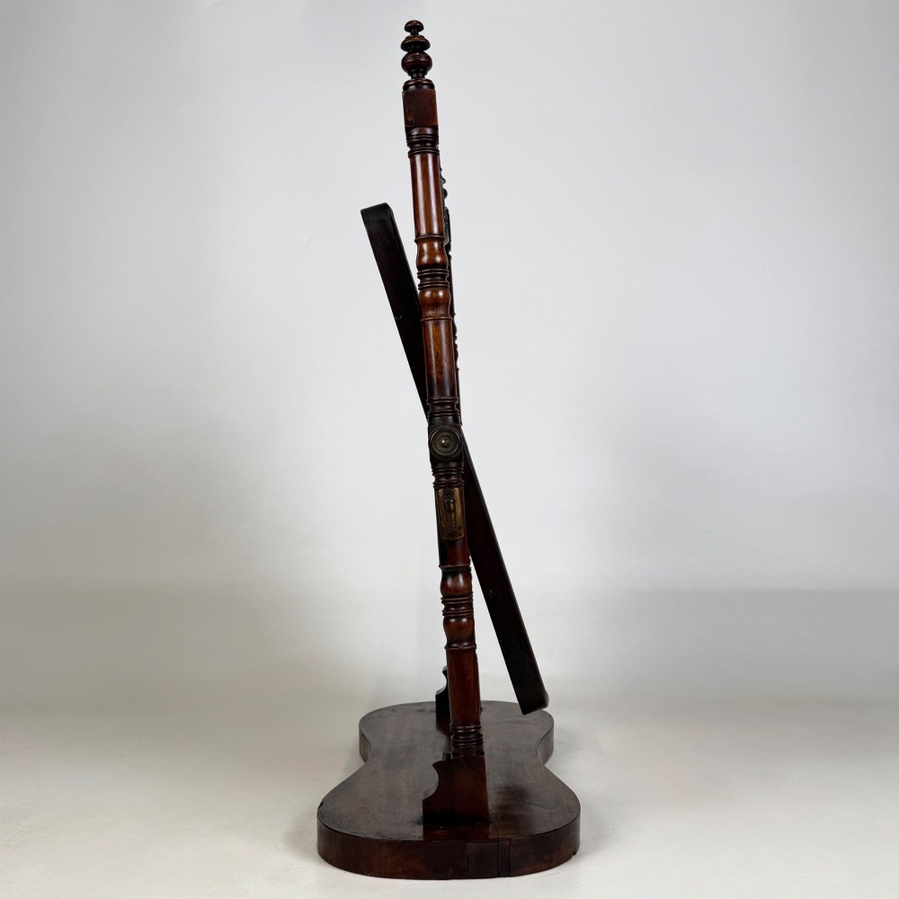 A 19th-century mahogany dressing mirror with turned side columns, carved scrollwork cresting, and an adjustable rectangular glass frame on a shaped base. View IX